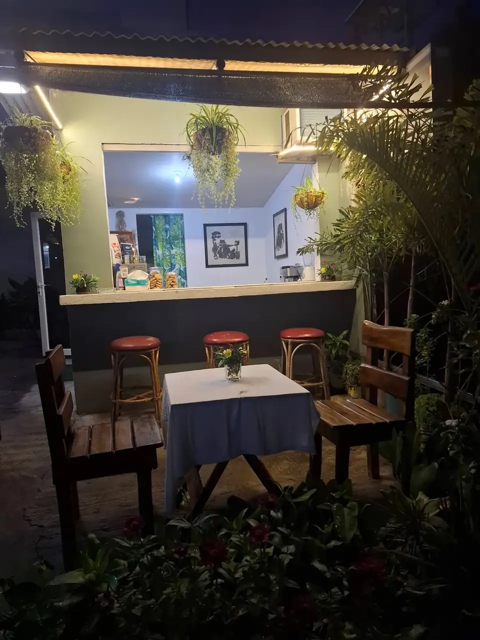 Kape Parola's open counter and wooden garden seating illuminated at night