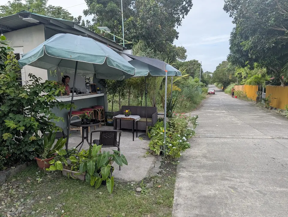Kape Parola's open-air roadside counter and seating beside the concrete lighthouse road