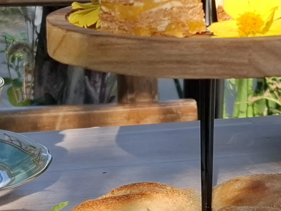 A floral teapot and teacups with cake and banana bread on the garden table at Kape Parola